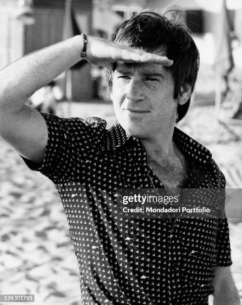 Italian actor Enzo Cerusico is on the beach, protecting himself from the sunlight with the right hand. Torvaianica, Rome , 1974..