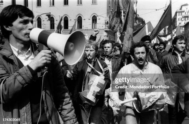 Group of demonstrators in the street protesting against unemployment; as well as party and union flags they are holding a megaphone and tin drums....