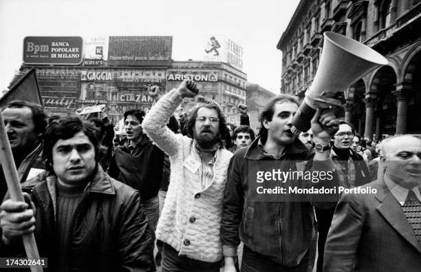 Workers striking for the defence of work in Duomo square in Milan; some of them are raising their fists while a young men is shouting on the...