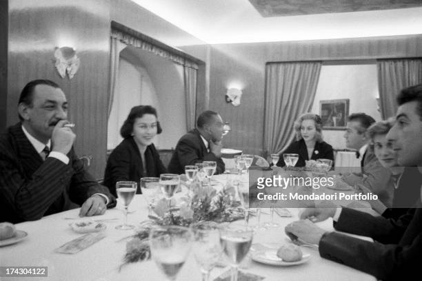 American writer Richard Wright talking to a woman sitting at a table with Italian publisher, journalist and writer Alberto Mondadori smoking a...
