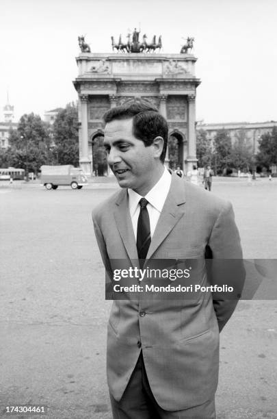 Italian presenter Corrado talking with his arms behind his back near Porta Sempione. Corrado is working on the TV broadcast l'Amico del giaguaro....