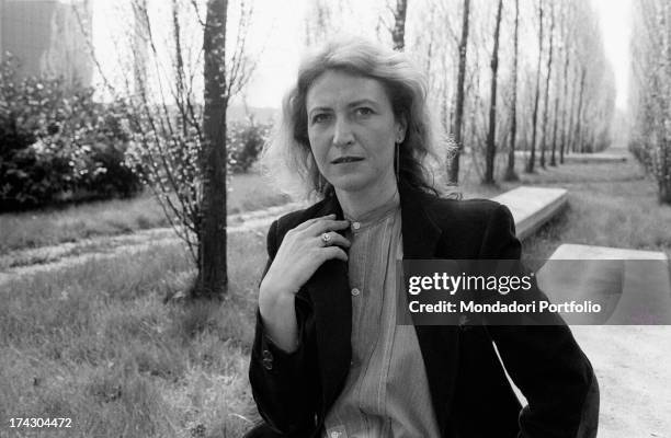 Italian writer and journalist Barbara Alberti sitting in a garden leaning her hand on her shoulder. 1970s.