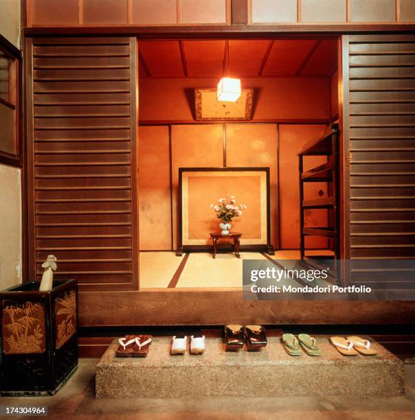 Five pair of mules arranged in an orderly way at the entrance of a Japanese house . Japan, 1960s.