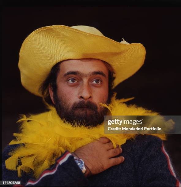 Close-up of the singer Lucio Dalla wearing a yellow straw hat and a yellow feather boa. Italy, 1967..