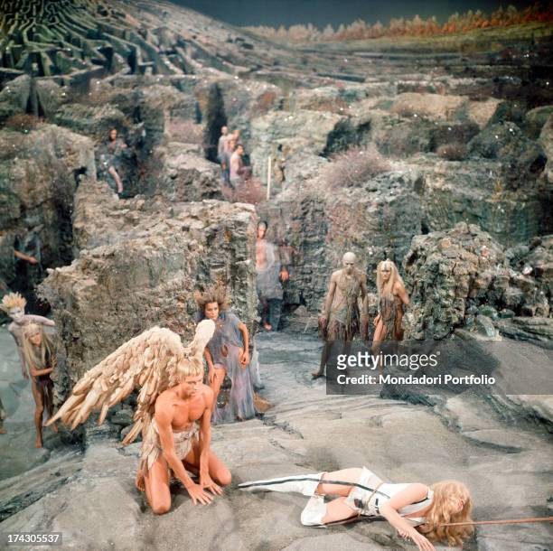 The American actors John Phillip Law and Jane Fonda on a rocky scenery, with extras, are playing in a scene of Roger Vadim's Barbarella; Fonda has...