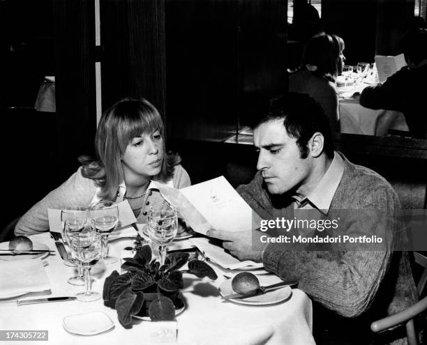 The Italian singer-songwriter Edoardo Vianello and his first wife Wilma Goich, an Italian singer, are seated at the table and read the menu. 1970..