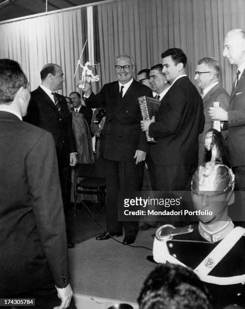 President of the Italian Republic Giuseppe Saragat smiling and raising the symbol of the Ignis household appliances' factory. Giuseppe Saragat...