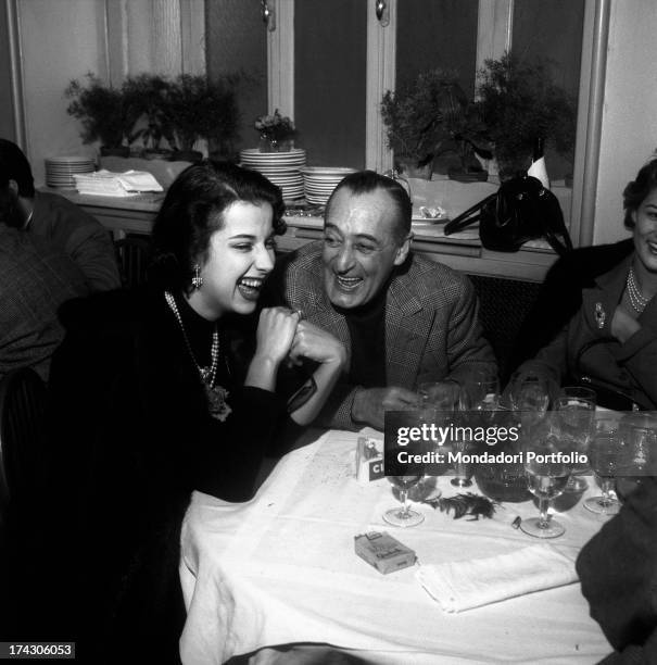 The comic actor from Naples Antonio de Curtis, known as Totò, is laughing at the table of a restaurant with his daughter Liliana and his partner, the...