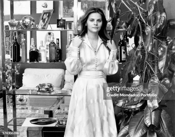 Italian actress Silvia Dionisio posing in a flat beside a plant. Rome, 1970s.