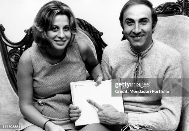 Italian TV presenter Pippo Baudo and his wife Angela Lippi pointing at the 7th December on a diary. Milan, 1970.