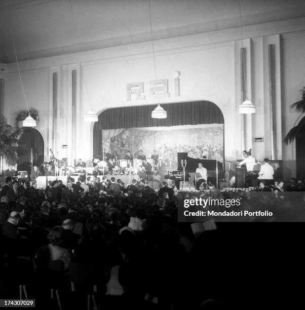 View of the stage of the Casinò di Sanremo where musicians are rehearsing the pieces of the IV Sanremo Music Festival; on the wall, over the curtain,...