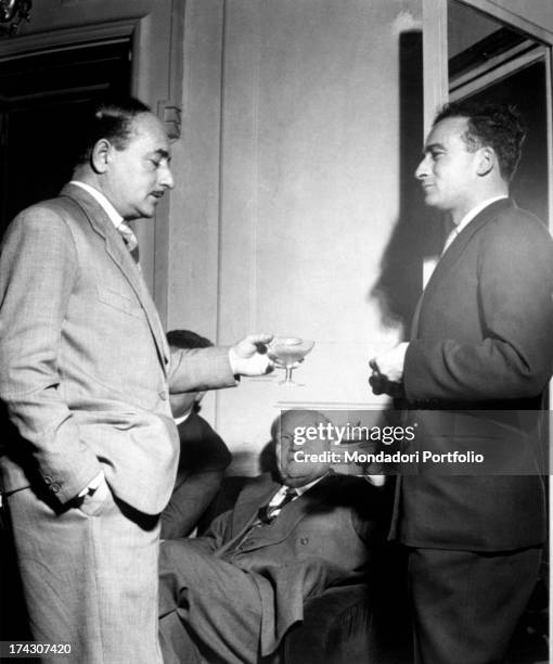 Toast between three great Italian writers: Salvatore Quasimodo, standing on the left, and Italo Calvino, on the right, together with Giuseppe...