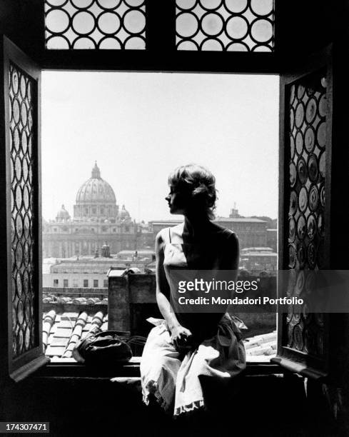 French actress Mijanou Bardot sitting on windowsill facing St Peter's Basilica. She is the sister of French actress Brigitte Bardot . Rome, 5th...