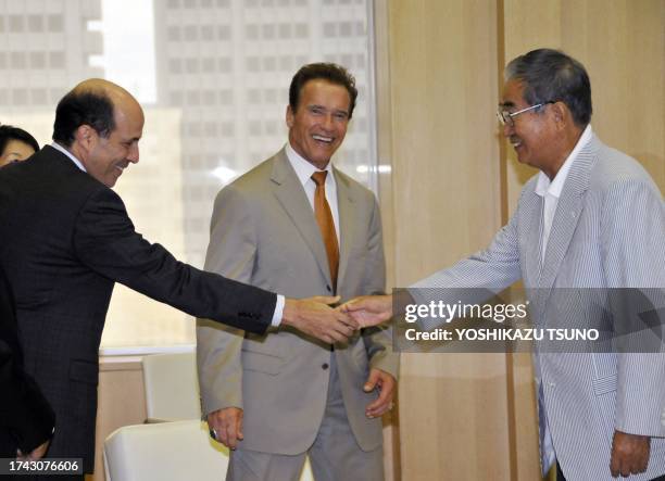 Ambassador to Japan John Roos shakes hands with Tokyo Governor Shintaro Ishihara, while California Governor Arnold Schwarzenegger looks on prior to...