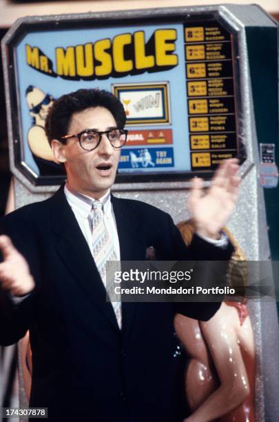 The Italian song-writer and singer from Sicily Francesco Battiato, known as Franco Battiato, is applauding; behind him a Mr. Muscle videogame testing...