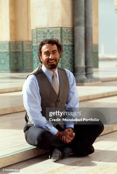 The Indian actor Kabir Bedi looks at the camera smiling, seated in the low step of an atrium in the newly built Mosque of Hassan II; he's in Morocco...