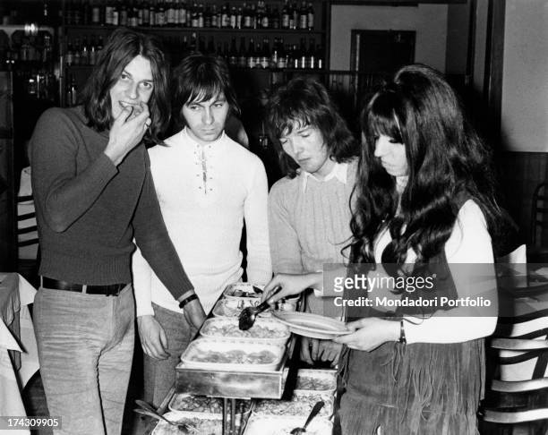 The four members of the Shocking Blue around the buffet of a restaurant, filling their dishes; the Dutch rock band reached number one in U.S. Chart...