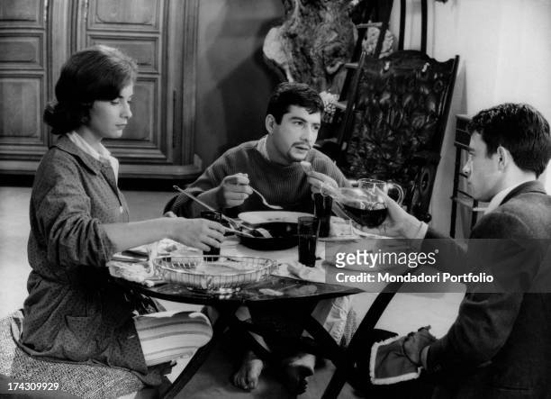 The French actors Juliette Mayniel, Jean-Claude Brialy and Gerard Blain are seated at a round table, having lunch, in a scene from Claude Chabrol's...