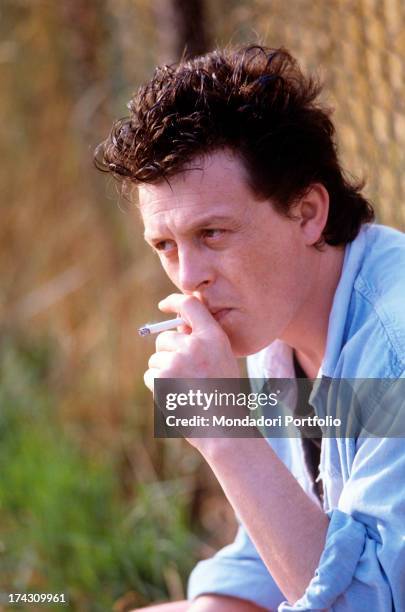 The Italian singer-songwriter Zucchero, Adelmo Fornaciari's pseudonym, smokes a cigarette gazing into the distance. Italy, 1986..