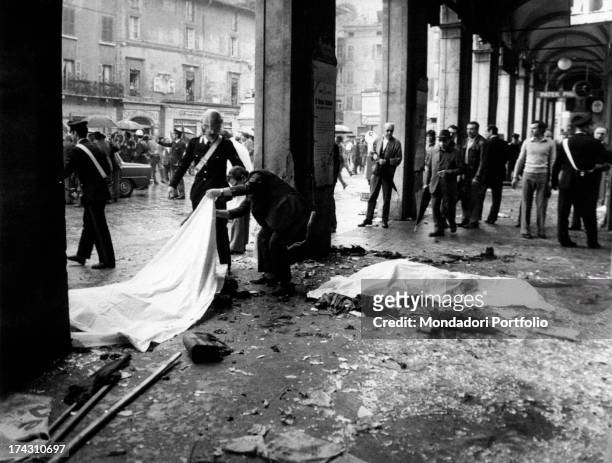Man lifting the sheet covering one of the victims of the massacre of Piazza della Loggia. Brescia, 28th May 1974 .