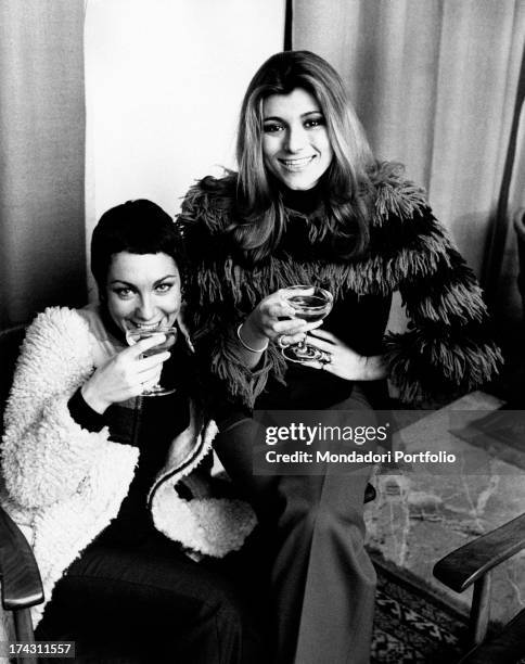 Italian singers and members of the band Ricchi e Poveri Marina Occhiena and Angela Brambati posing smiling with a glass of champagne in the hand....