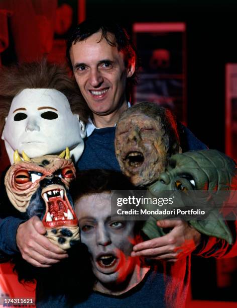 Italian director and scriptwriter Dario Argento posing inside his shop Profondo Rosso with some masks depicting horror characters. Rome, 1990.