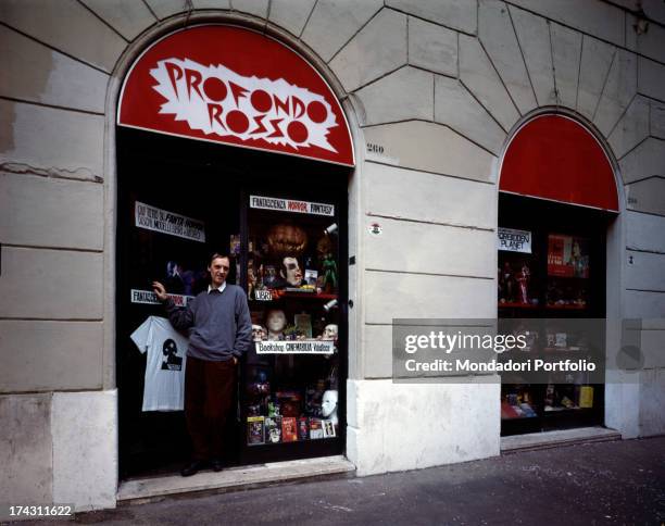 Italian director and scriptwriter Dario Argento posing at the entrance of his shop Profondo Rosso. Rome, 1990.