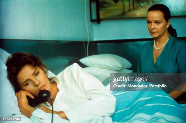 Italian actress Laura Antonelli assisting American actress Tahnee Welch lying in a hospital bed with a telephone in her hand in the TV series...