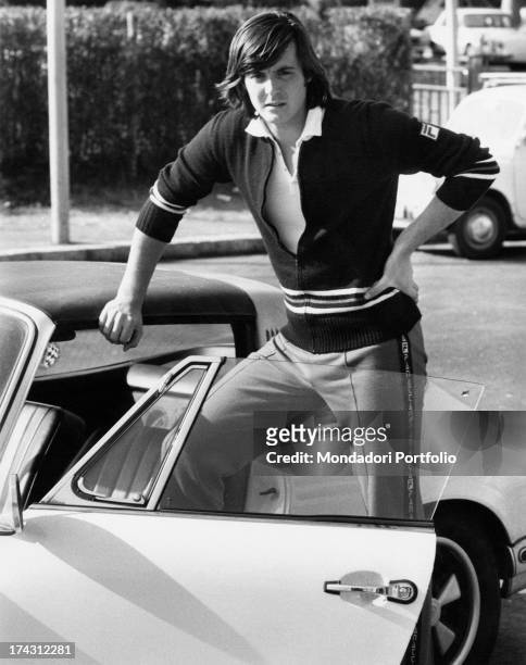 Italian tennis player Adriano Panatta posing leaning on a car. Rome, 1974.