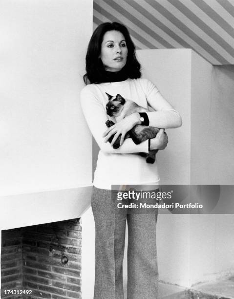 Italian television presenter and actress Gabriella Farinon holding a cat in her arms. Rome, 1970s.