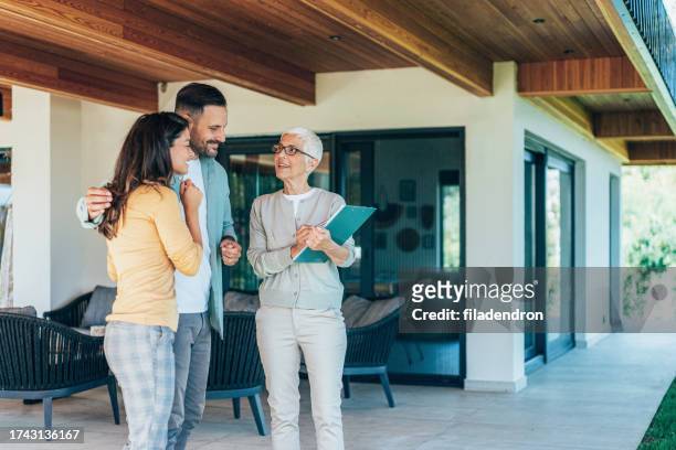 real estate agent showing a house for sale to a couple - property for sale stock pictures, royalty-free photos & images