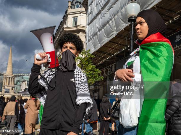 London, UK, A masked teenage boy holds a megaphone as he stands with his mother who is wrapped in a Palestinian Flag in central London, UK, at a...