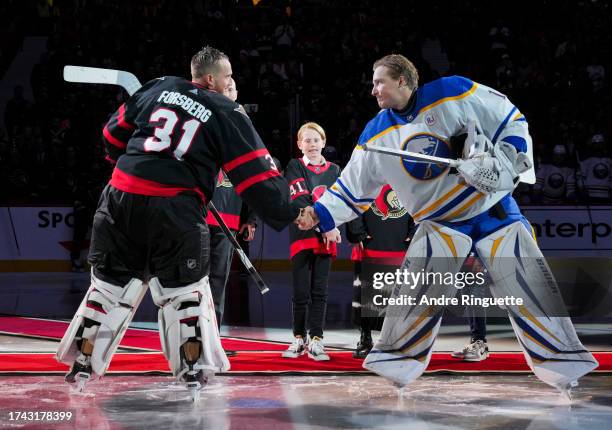 Anton Forsberg of the Ottawa Senators and Ukko-Pekka Luukkonen of the Buffalo Sabres shake hands after a ceremonial face-off recognizing Craig...