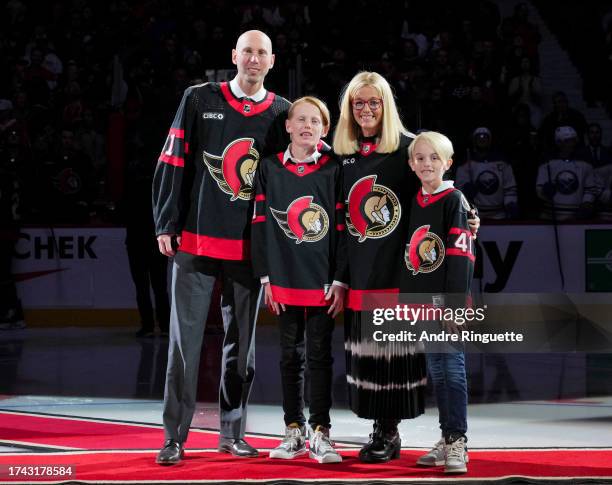 Craig Anderson, wife Nicholle and sons Jake Anderson and Levi Anderson pose for a photo during a pre-game ceremony after Anderson signed a one day...