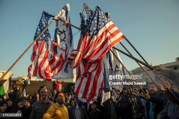 Iranian protestors prepare to set fire to the American and Israeli flags as they take part in a protest in support of Palestinians in Gaza at the...