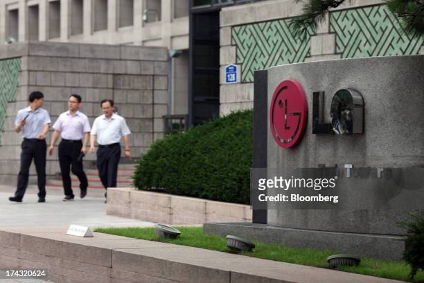 Pedestrians walk near signage for the LG Twin Towers, which houses LG Corp. Subsidiaries including LG Electronics Inc., LG Display Co., LG Chem Ltd....
