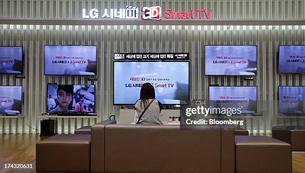 Customer sits in front of LG Electronics Inc. 3-D Smart televisions at one of the company's bestshop stores in the Gangnam area of Seoul, South...