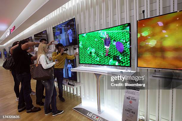 Customers photograph an LG Electronics Inc. Curved OLED television at one of the company's bestshop stores in the Gangnam area of Seoul, South Korea,...