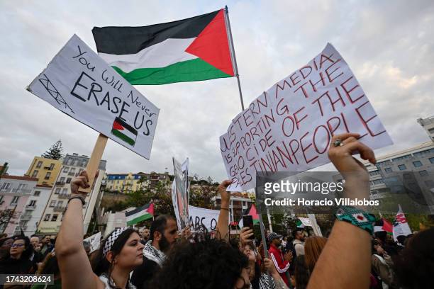 Participants hold Palestinian flags and protest signs against Israel during a demonstration and vigil in Martim Moniz Square organized by the...