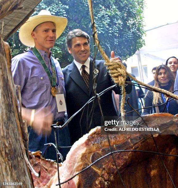 Texas Governor Rick Perry and US Olympic medalist Josh Davis watch food being prepared at a hotel in Mexico City, 23 August 2002. Perry is in Mexico...