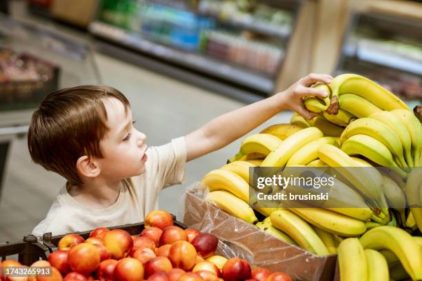 ragazzo di 6 anni che fa la spesa in un supermercato - solo bambini maschi foto e immagini stock