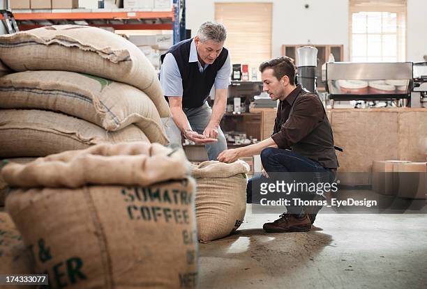 male owner of a coffee roasting business talking with worker - coffee bag stock pictures, royalty-free photos & images