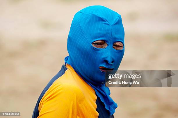 Chinese swimmer wearing body suit and protective head mask on a public beach on July 5, 2013 in Qingdao, China. Many Chinese beachgoers wearing their...