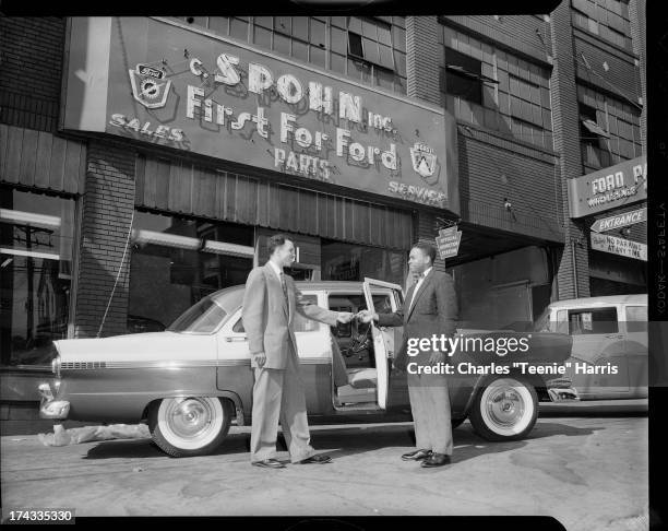 Mickey Wright handing keys for 1956 Ford car to Edward Fullum, in front of C. Spohn Inc. Ford dealership, 3131 Forbes Avenue, Oakland, Pittsburgh,...