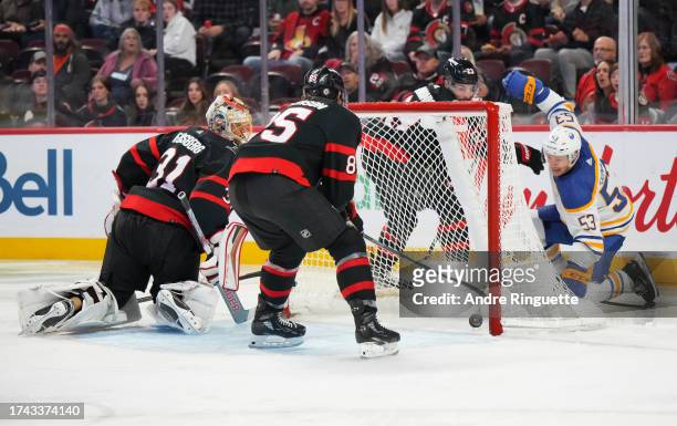 Jake Sanderson of the Ottawa Senators tries to clears the puck off the goal-line of Anton Forsberg after Jeff Skinner of the Buffalo Sabres battles...