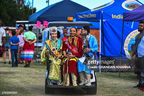 Women in indigenous costumes sit in a gold cart during a cultural meeting at the Comanche Nation fairgrounds in Lawton, Oklahoma on September 30,...