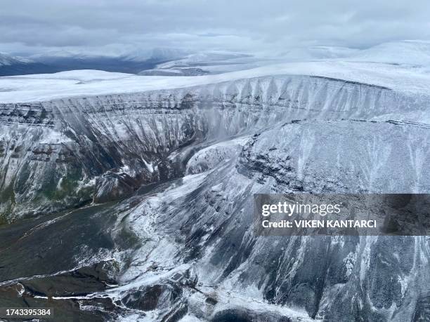 An aerial view captured from a helicopter shows the ice cap, snow and rivers on top of mountains in the Arctic Norwegian Svalbard Archipelago,...