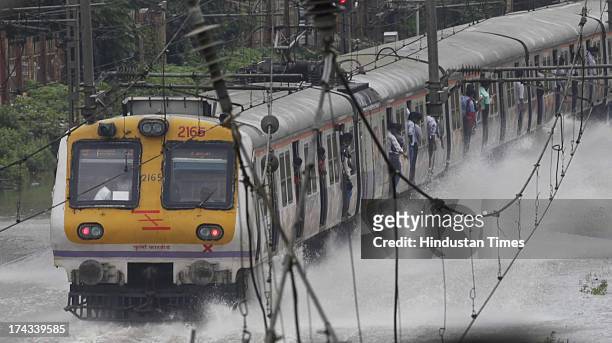 Mumbai local train go through the flooded railroad tracks during heavy rain showers and water logged near Kurla - Cunabhatti on July 24, 2013 IN...