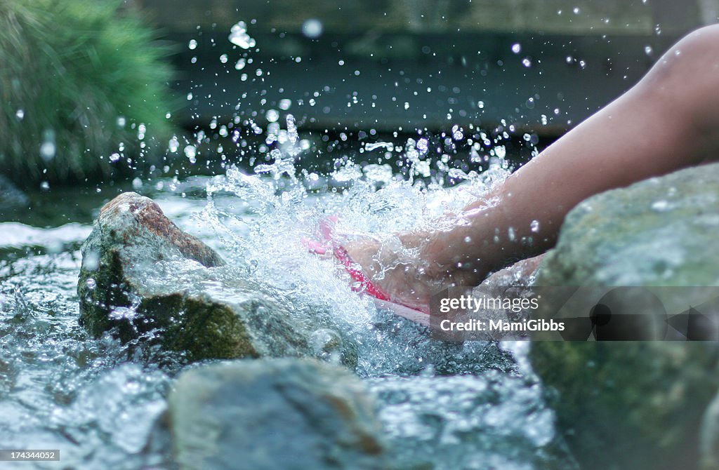 Girl's foot kicking water on the river.