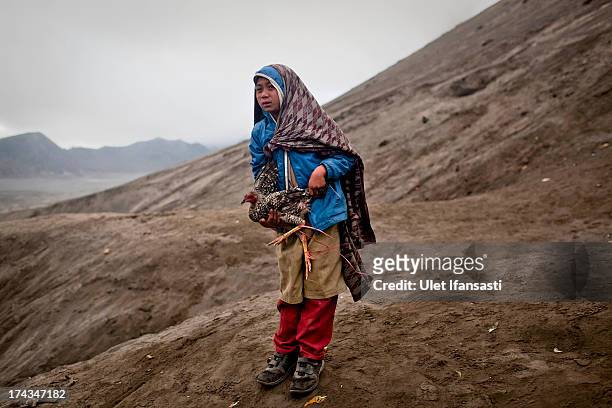 Doni, holds a chicken thrown by Hindu worshippers at the foot of Mount Bromo during the Yadnya Kasada Festival at crater of Mount Bromo on July 24,...
